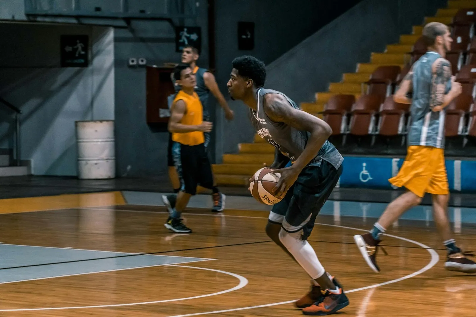 Basketball player wearing compression knee pads on indoor hardwood court